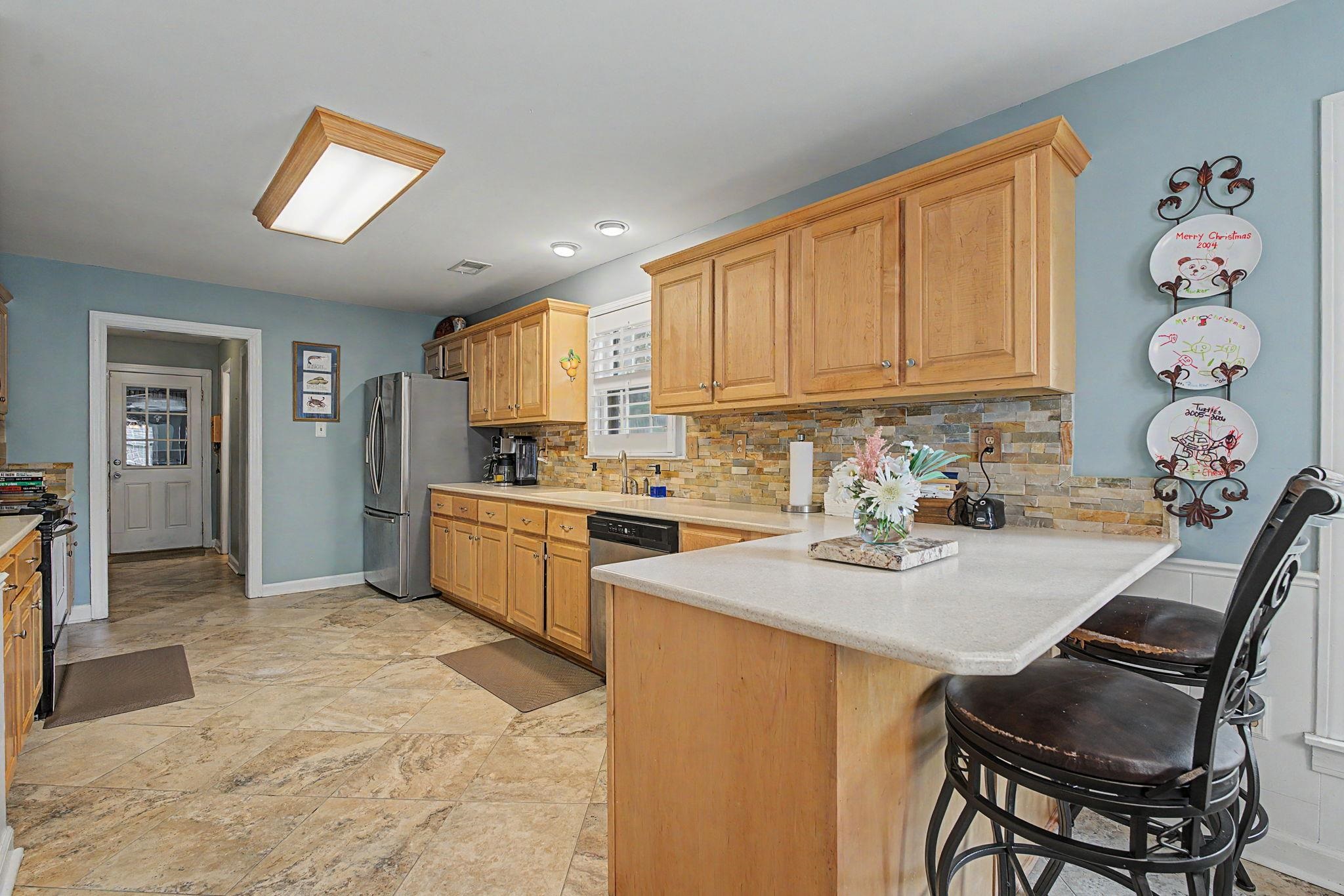 1929 Miller Farms Road Germantown, TN 38138 - Photo 14 of 40 Kitchen featuring light wood cabinetry, stone-look tile flooring, and a multi-tone stone backsplash