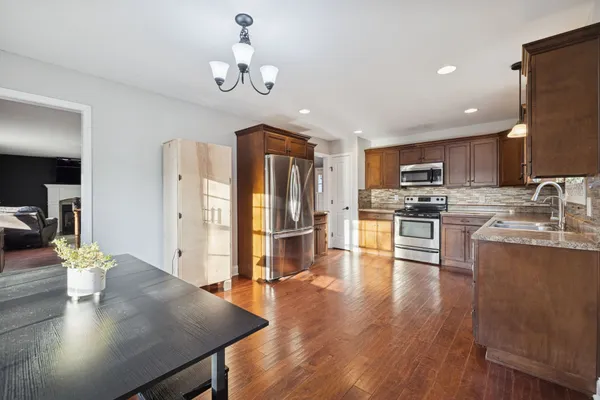 a kitchen with stainless steel appliances granite countertop a refrigerator a stove top oven a sink dishwasher and white cabinets with wooden floor