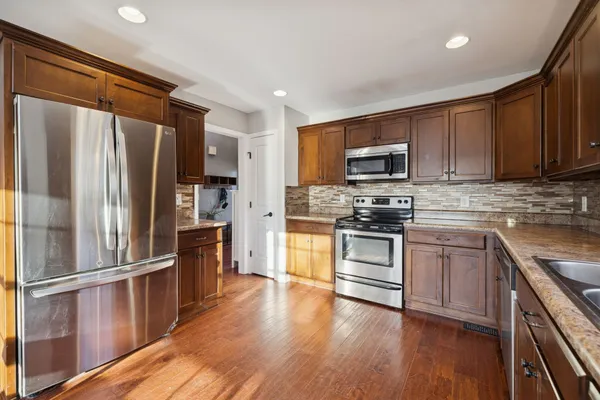 a kitchen with granite countertop wooden floors stainless steel appliances and a window