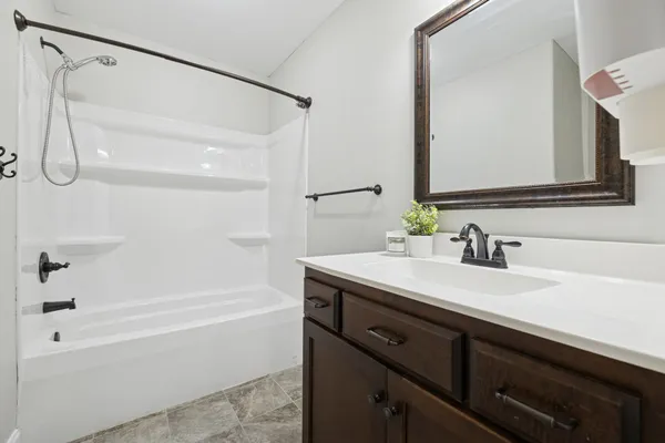 a bathroom with a granite countertop sink mirror and a bathtub
