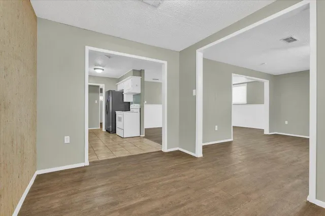 a view of a hallway with wooden floor and a bathroom