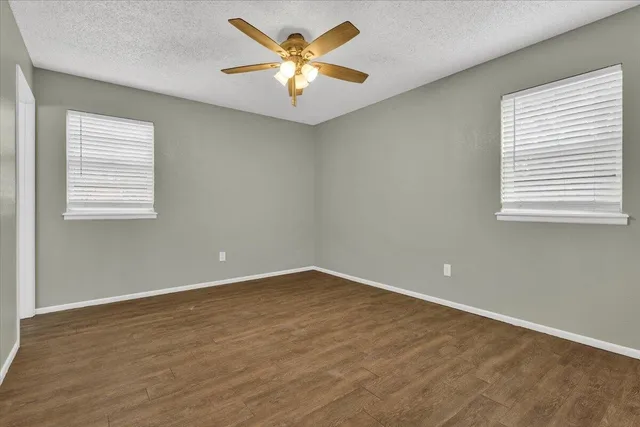 an empty room with a window and a chandelier fan