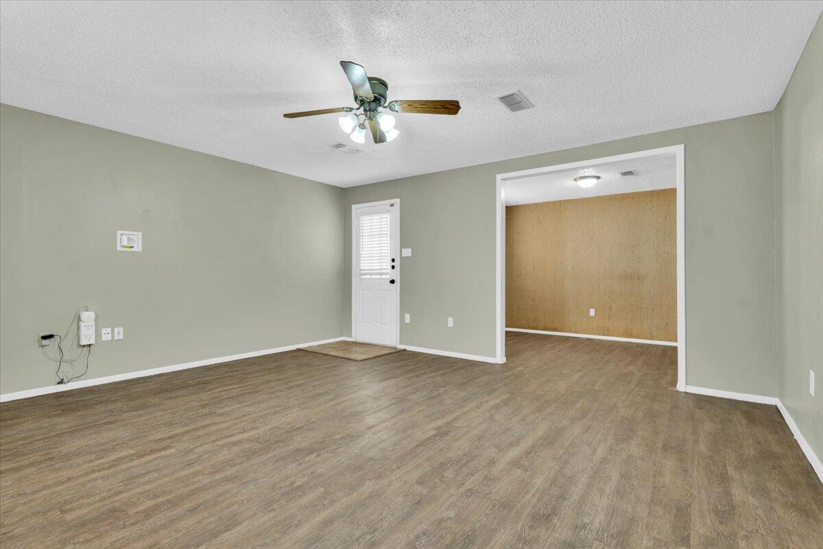 4802 54th Street Lubbock, TX 79414 - Photo 7 of 27 a view of an empty room with wooden floor and a ceiling fan