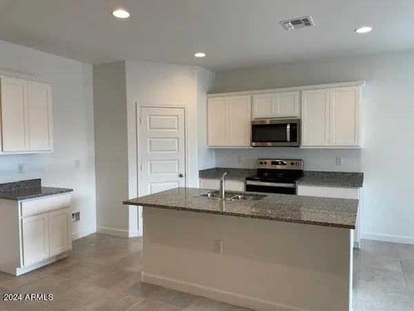 a kitchen with stainless steel appliances granite countertop a sink a stove a microwave a sink a refrigerator and cabinets