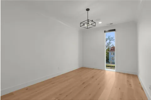 a kitchen with kitchen island a stove a refrigerator and white cabinets with wooden floor