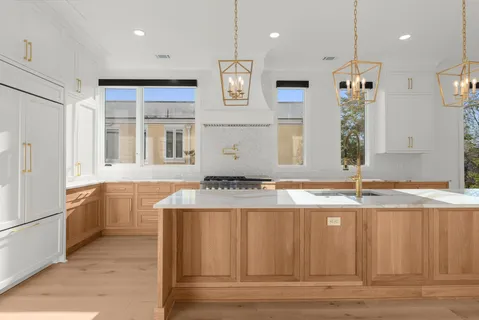 a large kitchen with stainless steel appliances granite countertop a refrigerator a oven and a wooden cabinets