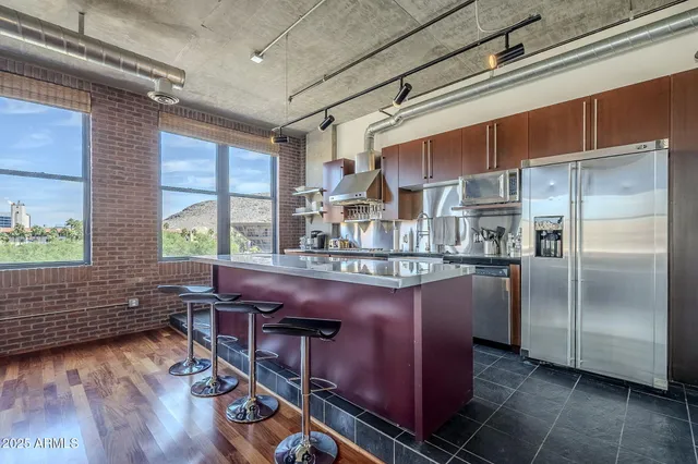 a kitchen with stainless steel appliances granite countertop a refrigerator a sink dishwasher a stove and white countertops with wooden floor