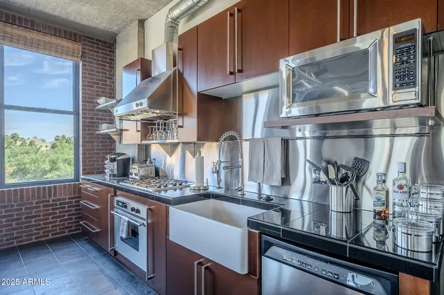 a kitchen with stainless steel appliances granite countertop a sink and wooden cabinets