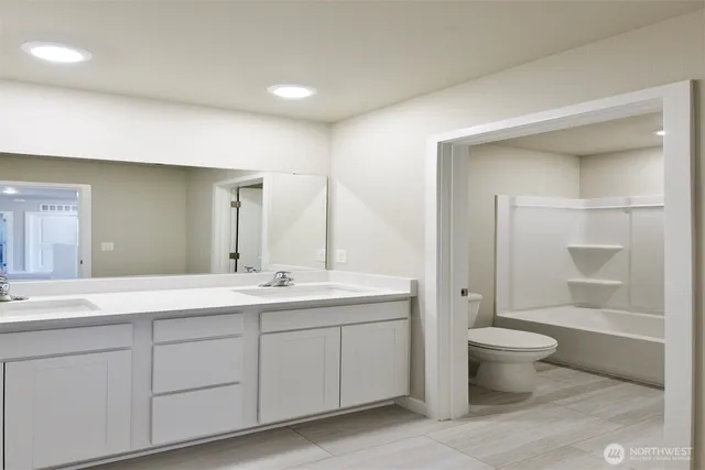 a spacious bathroom with a double vanity sink toilet and a mirror