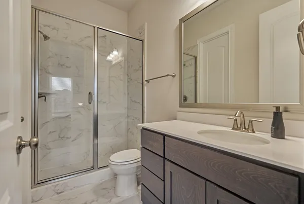 a bathroom with a shower sink vanity mirror and toilet