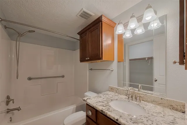 a bathroom with a granite countertop sink a toilet and shower