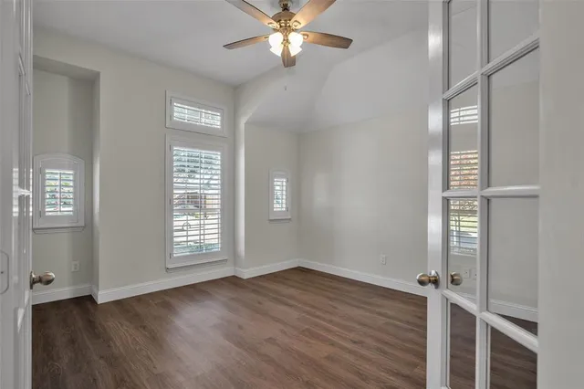 an empty room with wooden floor closet and windows