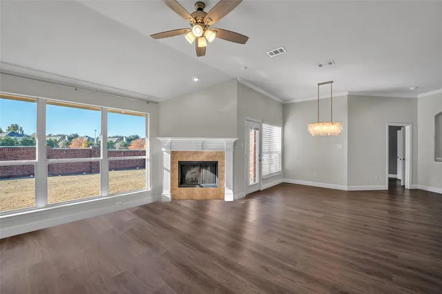 an empty room with wooden floor fireplace and windows