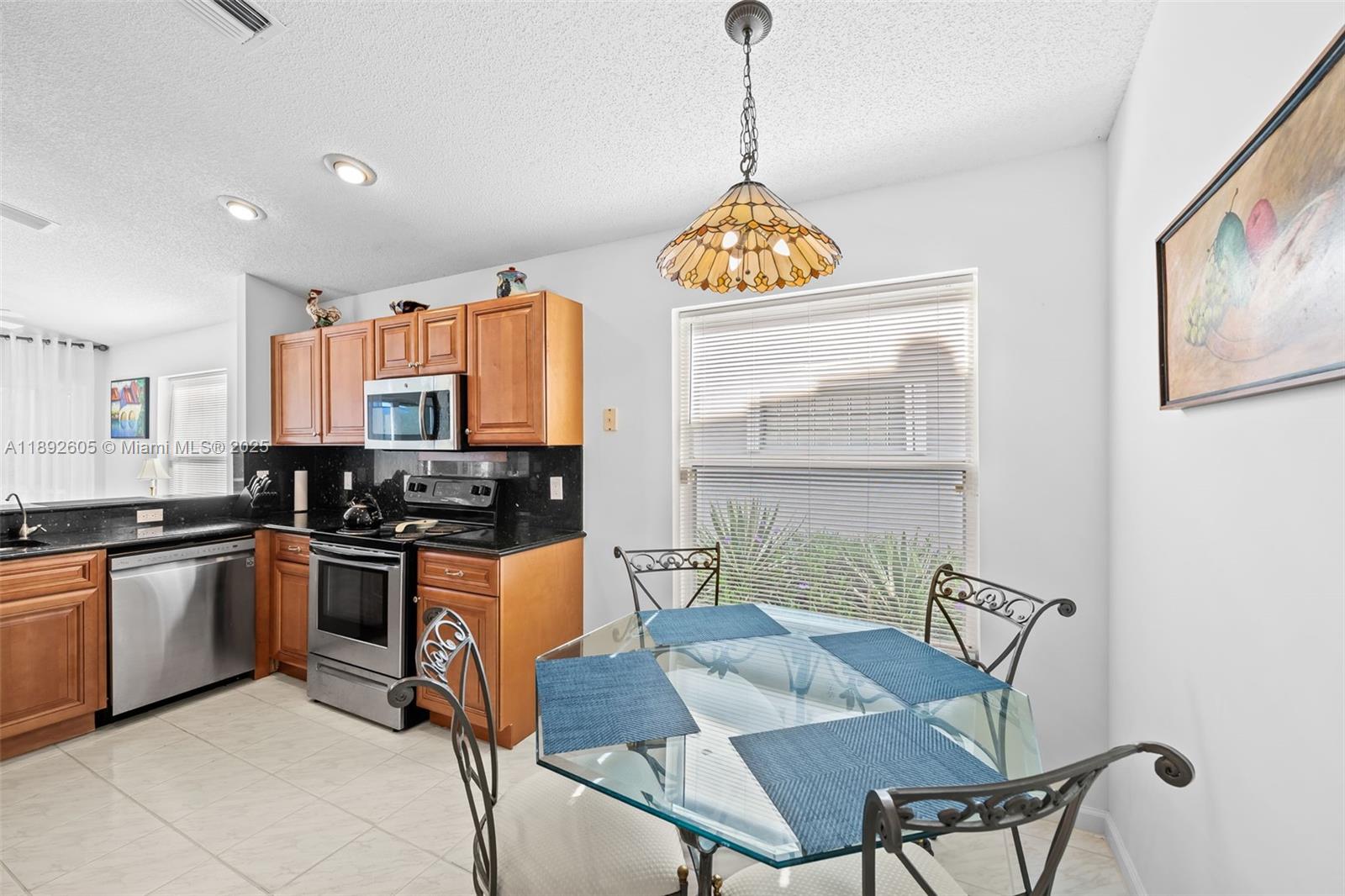 9650 Harbour Lake Circle Boynton Beach, FL 33437 - Photo 5 of 25 a kitchen with stainless steel appliances granite countertop a stove a sink dishwasher a dining table and chairs with wooden floor