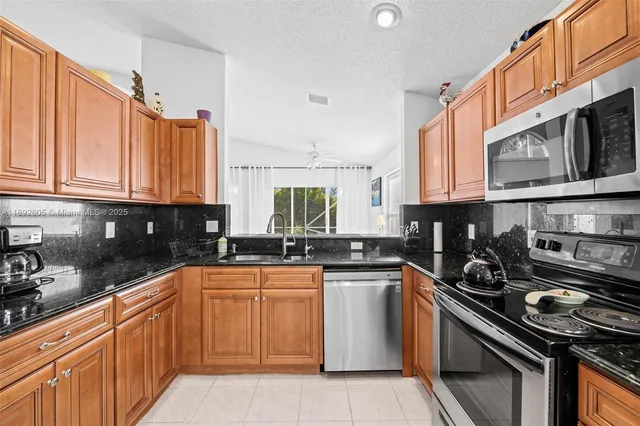 a kitchen with stainless steel appliances granite countertop a sink a stove a microwave and cabinets