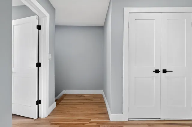 a view of a hallway with wooden floor and closet