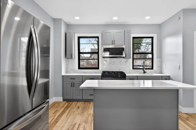 a large kitchen with stainless steel appliances granite countertop a refrigerator a sink a stove and a microwave