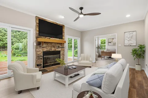 a living room with furniture a fireplace a flat screen tv and a large window