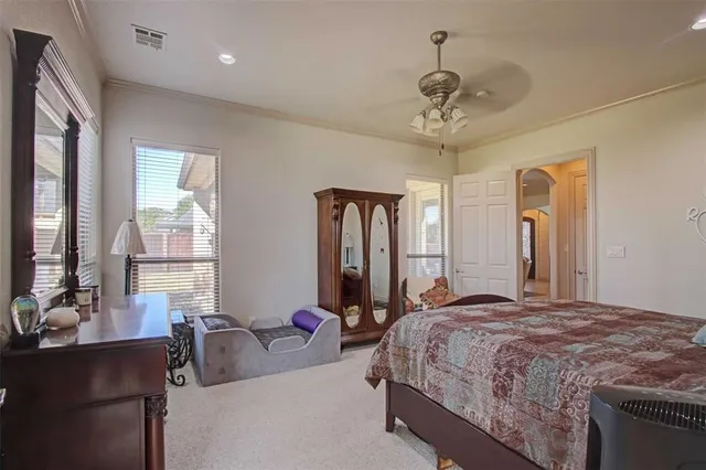 a spacious bedroom with a bed a chandelier and mirror