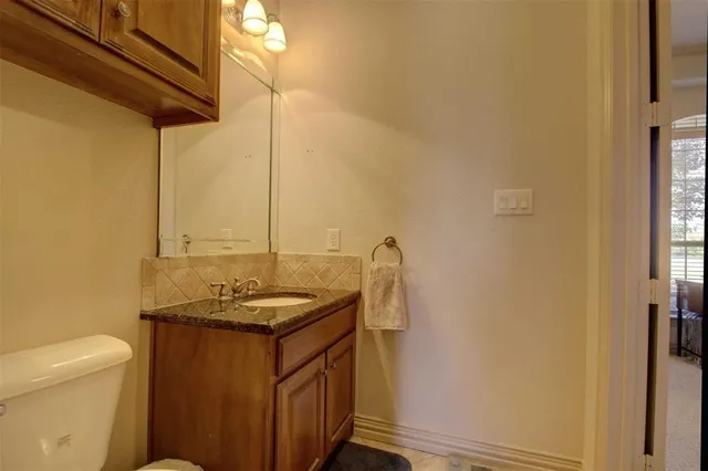 a bathroom with a granite countertop sink and a toilet