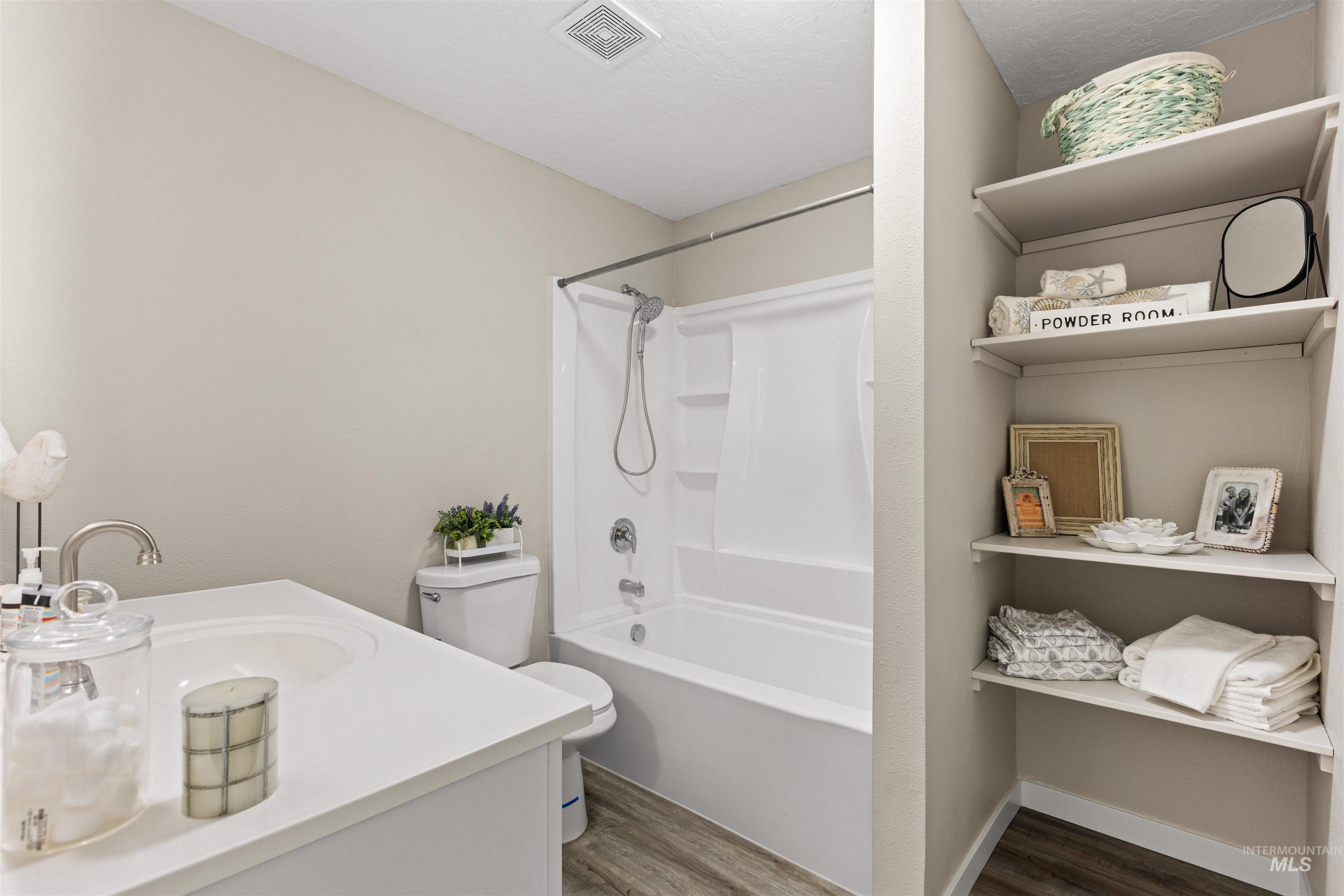 12184 Hill Road Payette, ID 83661 - Photo 25 of 35 Bathroom featuring a single vanity with an integrated sink, brushed nickel faucet, a white toilet, and a combined tub and shower unit
