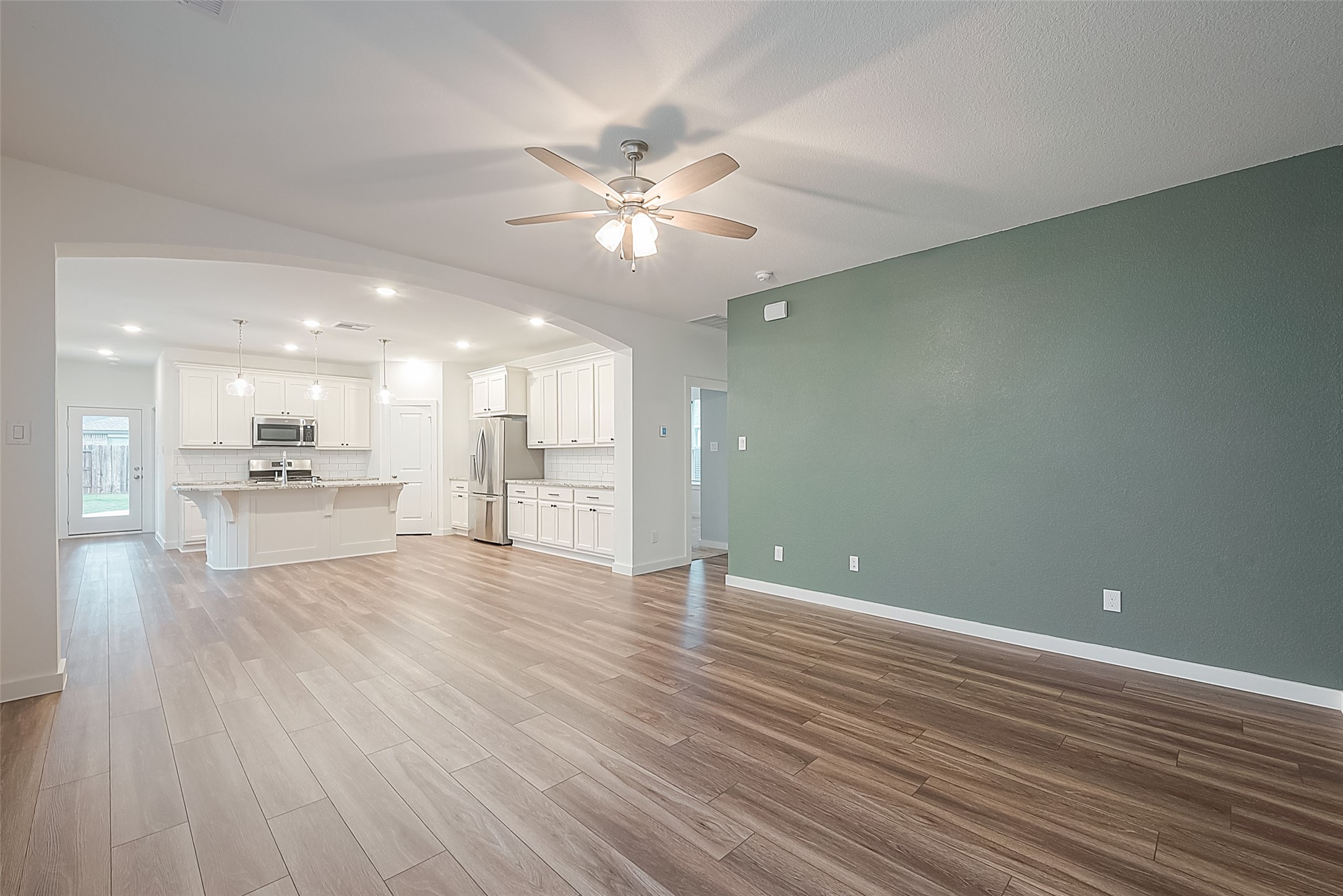 516 Timber Voyage Court Conroe, TX 77304 - Photo 6 of 25 a view of an empty room with wooden floor and a kitchen