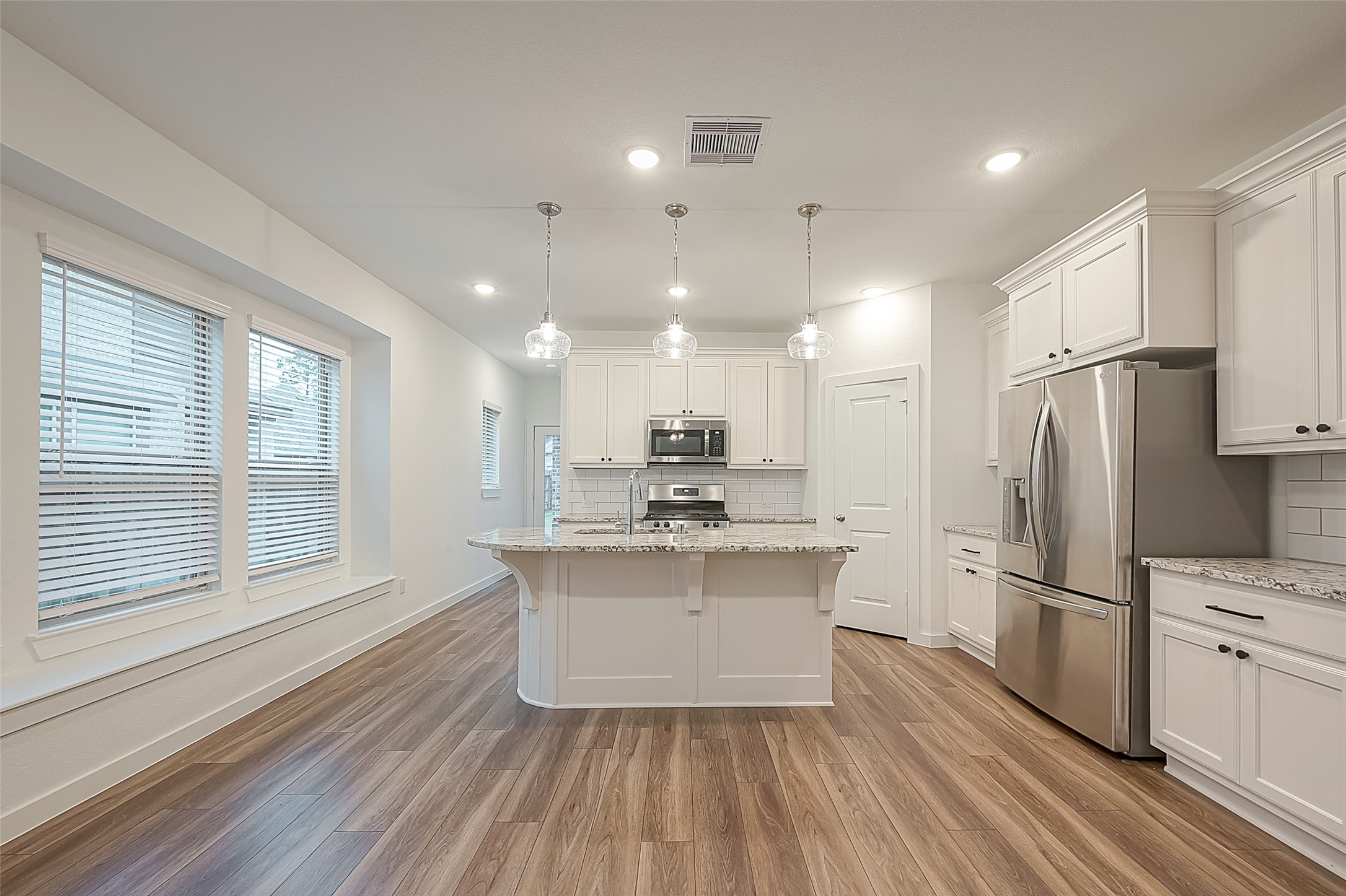 516 Timber Voyage Court Conroe, TX 77304 - Photo 9 of 25 a kitchen with kitchen island white cabinets stainless steel appliances a sink and a large window