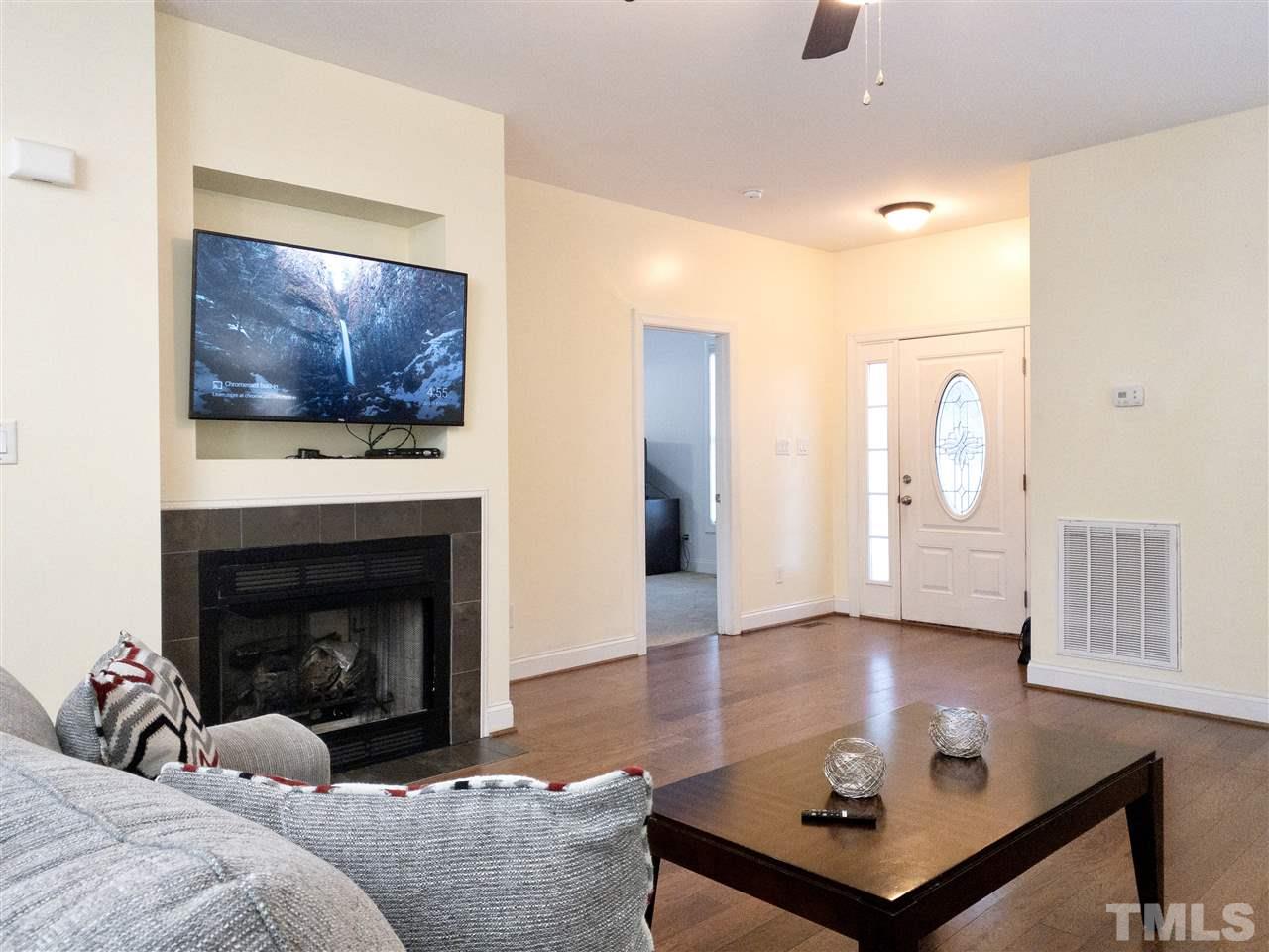 2513 Friendly Trail Raleigh, NC 27610 - Photo 8 of 29 a living room with furniture a fireplace and a flat screen tv