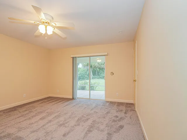 an empty room with a chandelier fan and windows