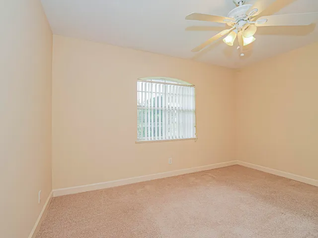 an empty room with a window and a ceiling fan