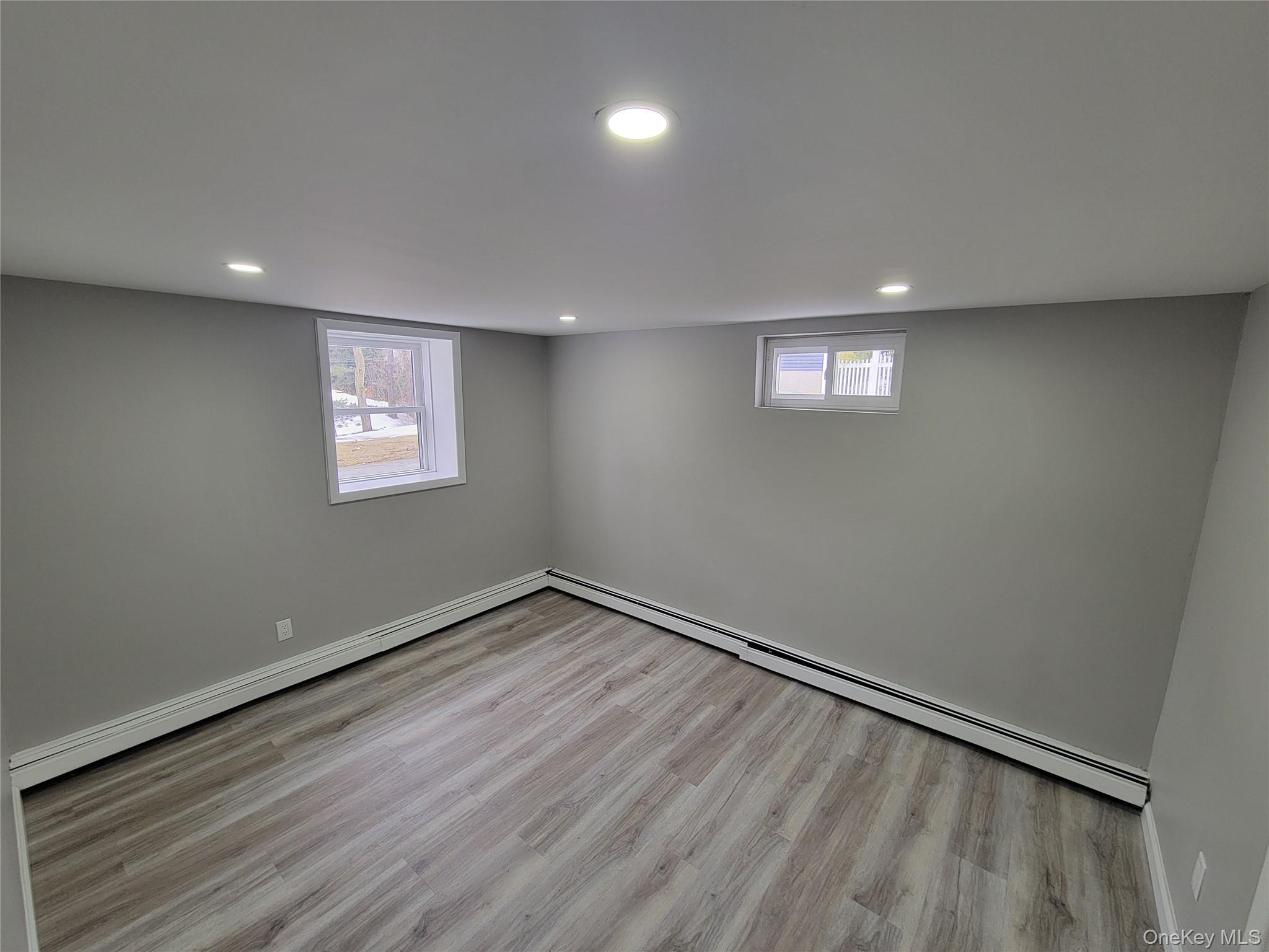 96 Hallock Landing Road Rocky Point, NY 11778 - Photo 8 of 13 an empty room with wooden floor and windows
