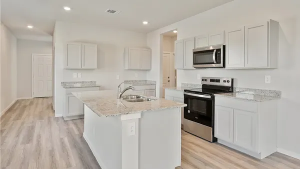 a kitchen with stainless steel appliances granite countertop a sink dishwasher a stove and a microwave oven with white cabinets