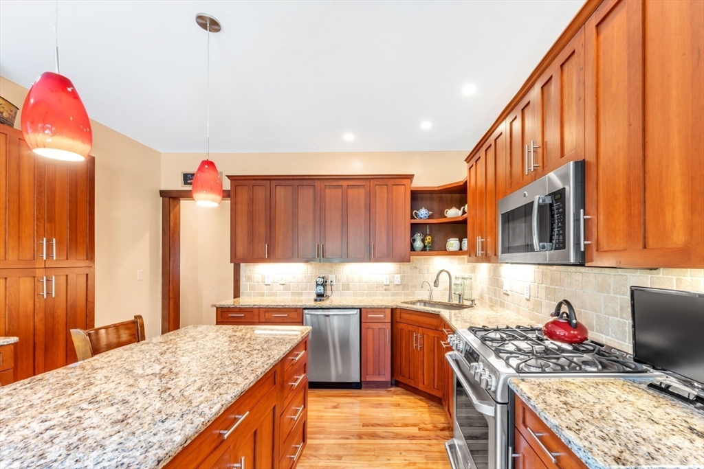 53 B Burroughs Street Boston, MA 02130 - Photo 11 of 41 a kitchen with stainless steel appliances granite countertop a stove top oven a sink dishwasher and cabinets with wooden floor