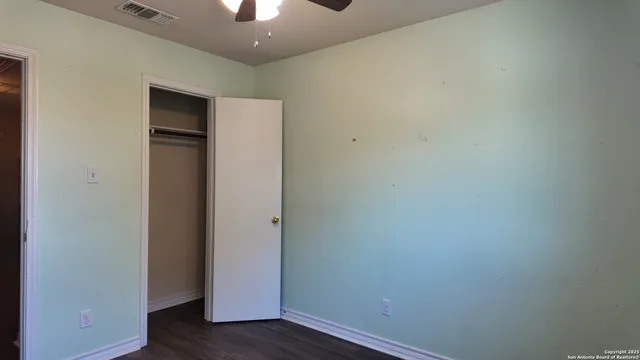 a view of an empty room with wooden floor and closet