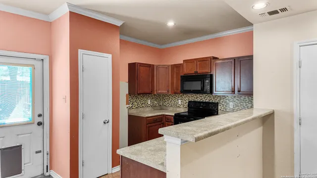 a kitchen view with stainless steel appliances wooden cabinets and a counter top space