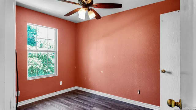 an empty room with windows and fan