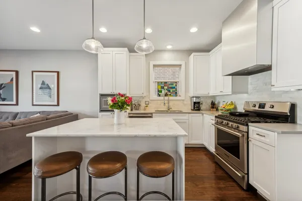 a kitchen with stainless steel appliances a table chairs sink and stove top oven