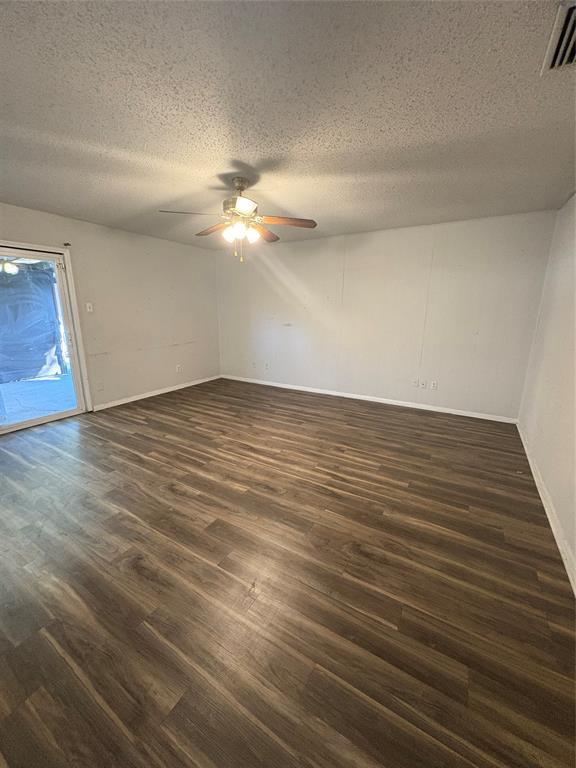 3717 Swallow Lane Irving, TX 75062 - Photo 5 of 11 Unfurnished room featuring a textured ceiling, dark wood-style floors, and a ceiling fan