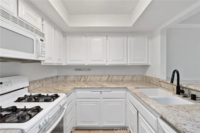 a kitchen with granite countertop a sink and white cabinets
