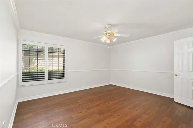 an empty room with wooden floor and ceiling fan
