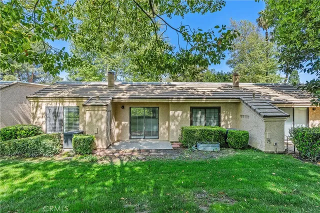 a view of a house with a yard potted plants and a large tree