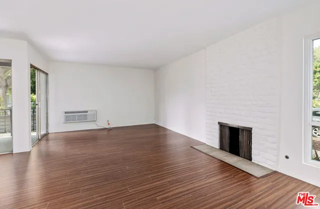 a view of empty room with wooden floor and fireplace