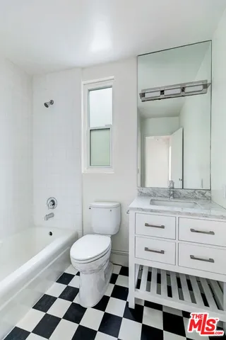 a bathroom with a granite countertop toilet a sink a mirror a bathtub and shower