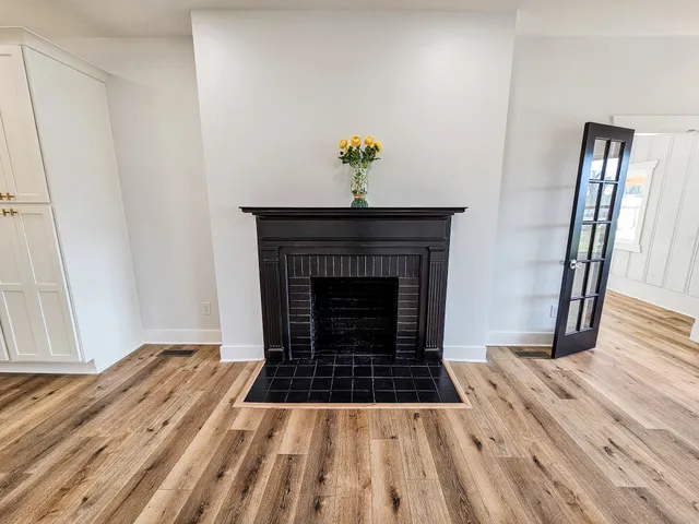 a large white kitchen with wooden floor and stainless steel appliances
