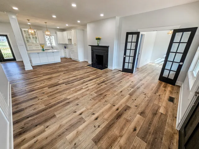 a view of an empty room with wooden floor and a fireplace