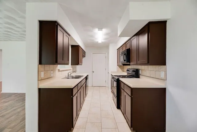 a kitchen with stainless steel appliances kitchen island granite countertop a sink stove and cabinets