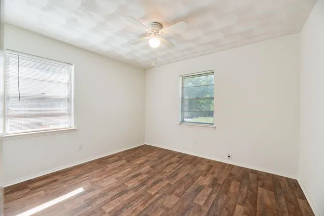 an empty room with windows and fan
