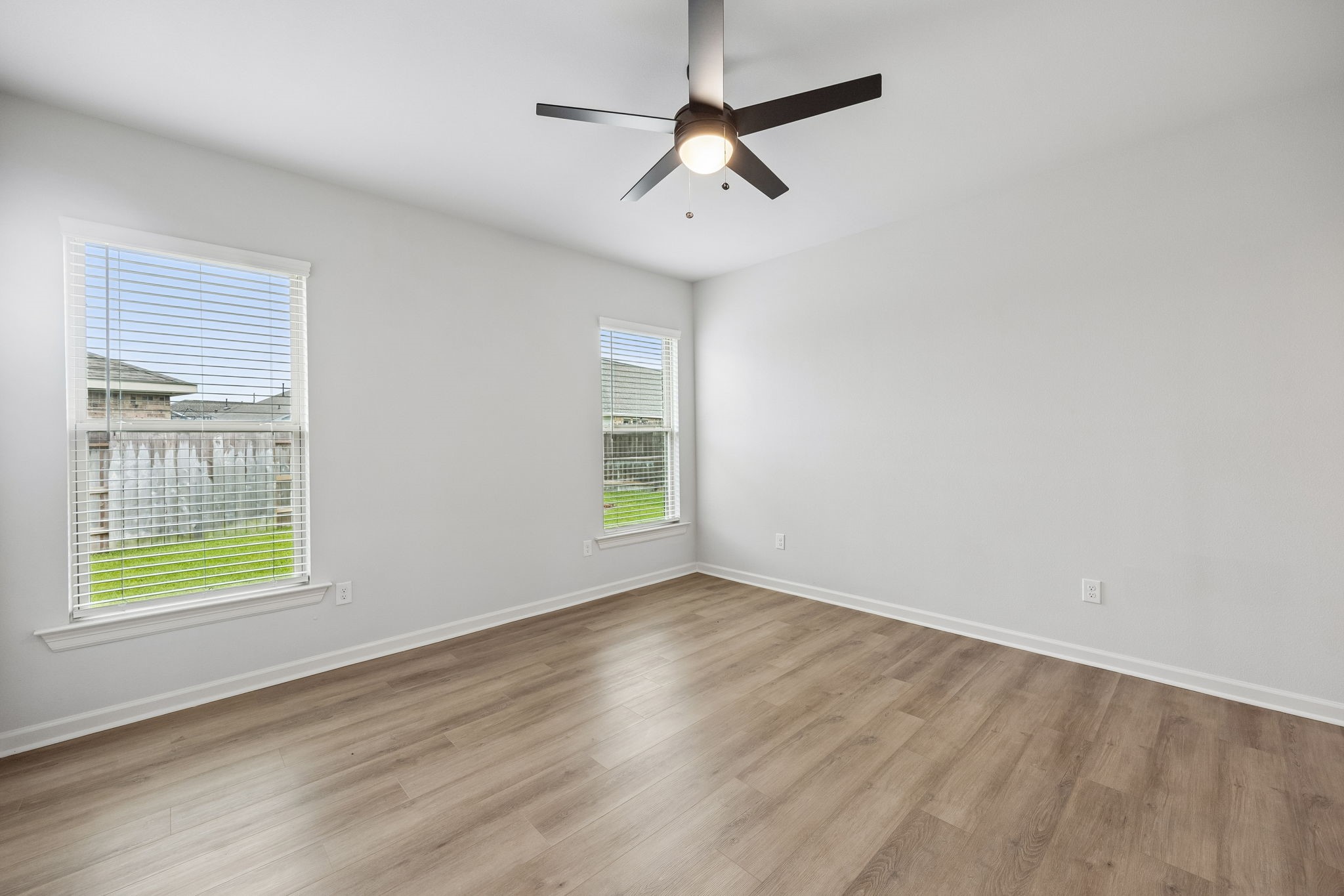 10902 Bonfire Trail Beasley, TX 77417 - Photo 12 of 36 This primary bedroom features fresh, light-color walls and vinyl plank flooring, creating a bright and airy feel. It has two large windows offering natural light and a ceiling fan for comfort.