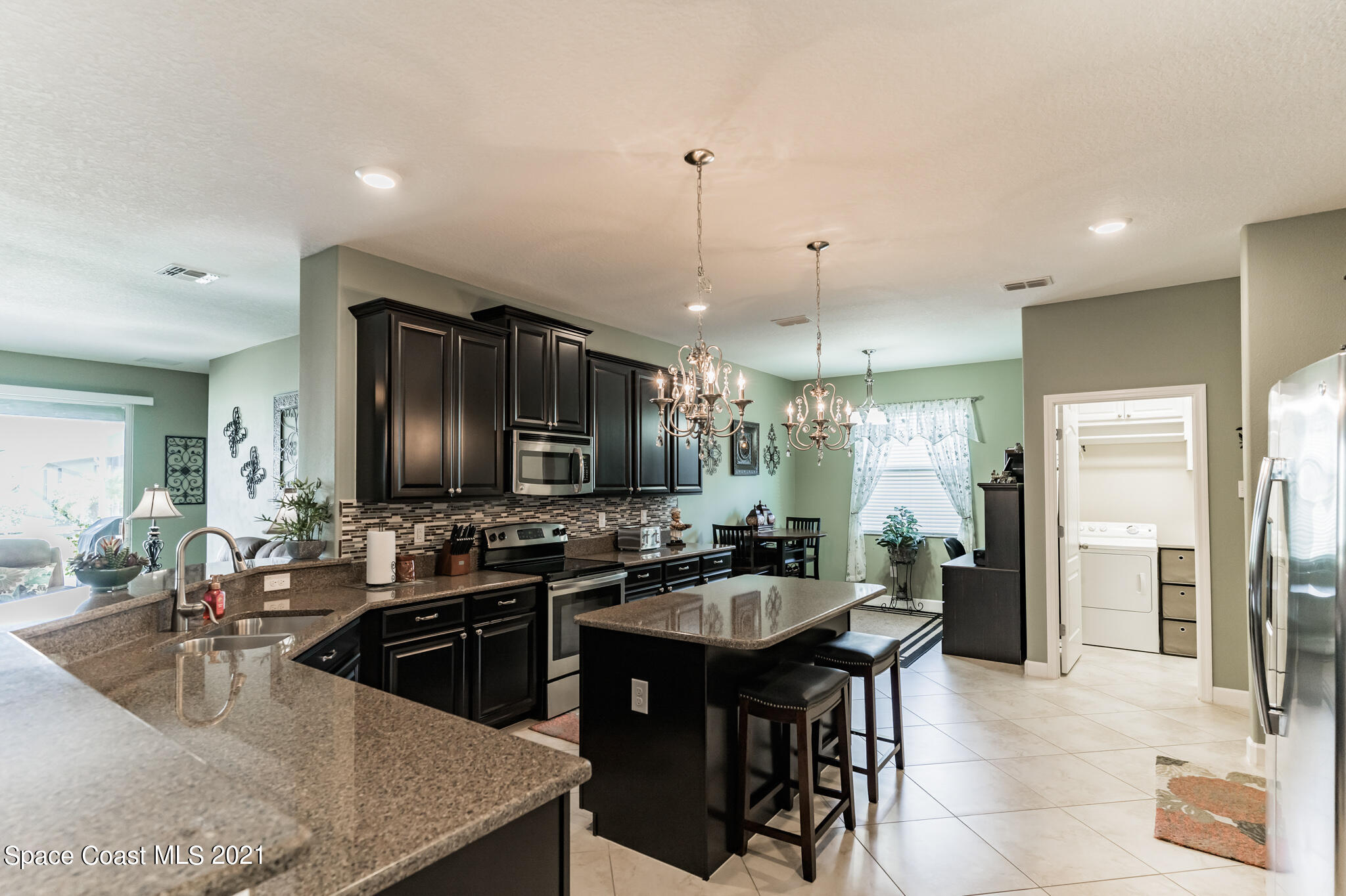 3242 Balboa Place Melbourne, FL 32940 - Photo 3 of 34 a kitchen with a sink a stove a dining table and chairs