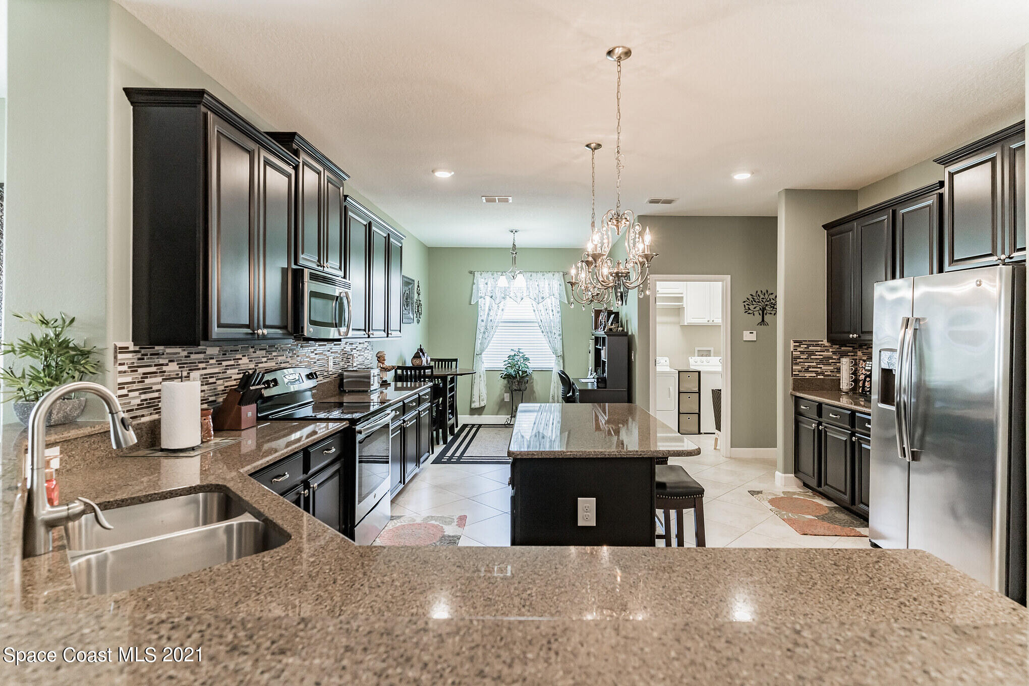 3242 Balboa Place Melbourne, FL 32940 - Photo 5 of 34 a kitchen with stainless steel appliances kitchen island granite countertop a refrigerator and a sink